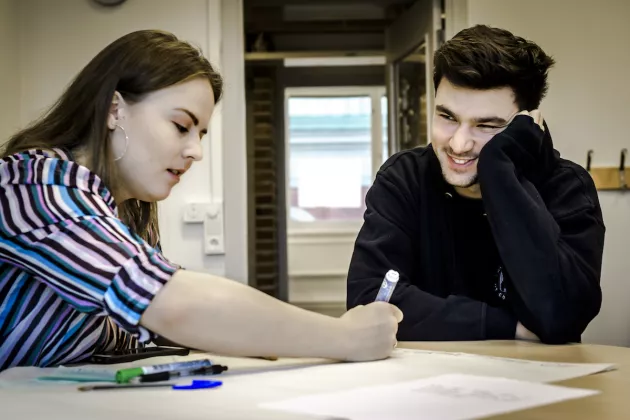 Two students working together at a desk. Photo